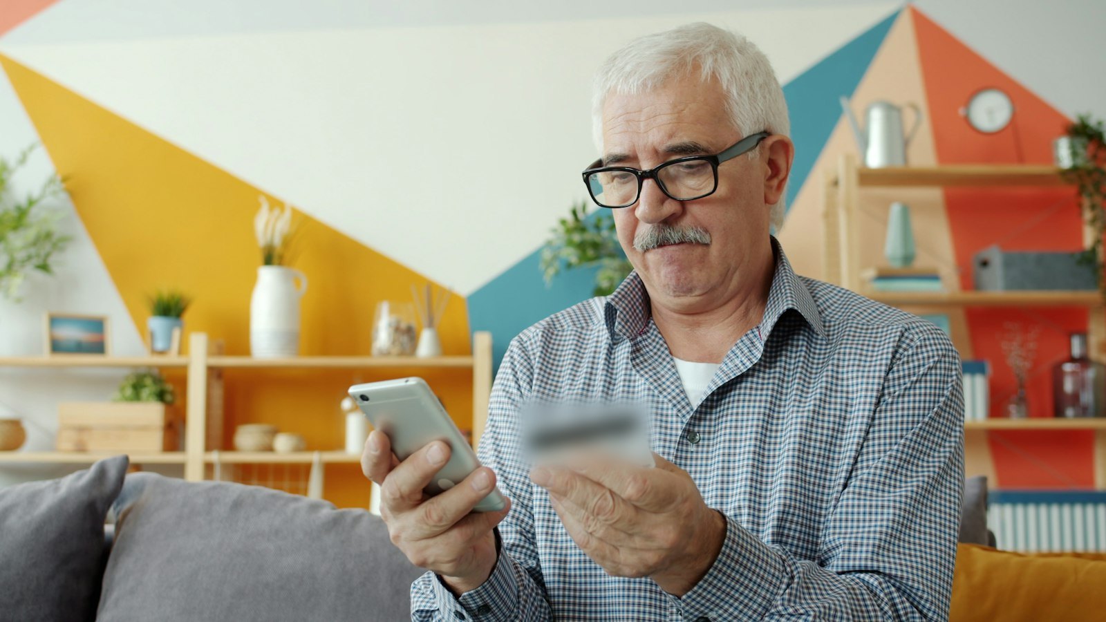 An older man at home shopping online on his phone